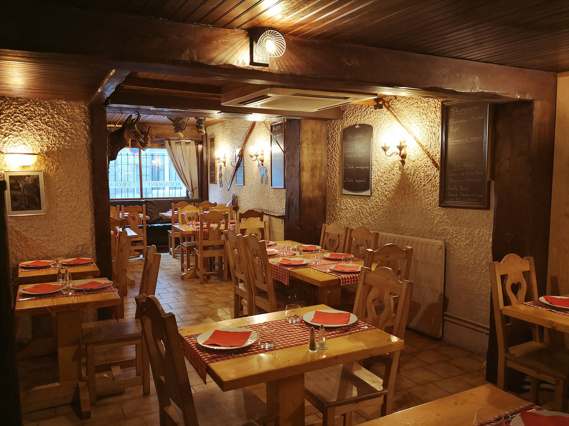 La salle du restaurant Le Chamois : tables en bois, nappes à carreaux rouges et décor de chalet